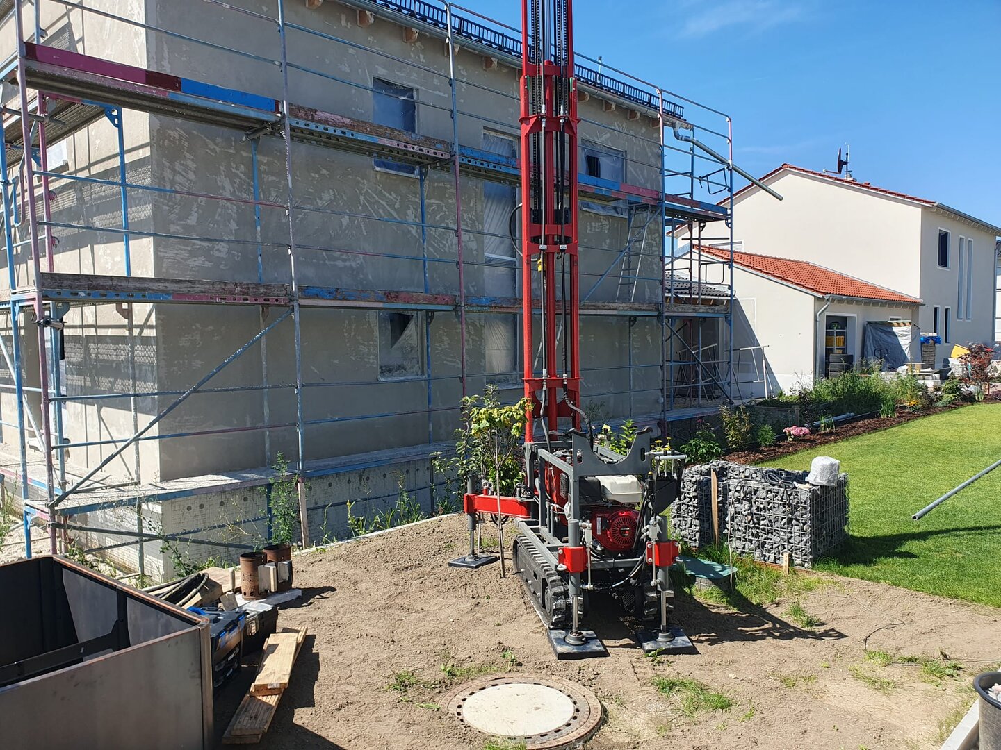 Brunnenbohrung mit kompaktem Gerät neben einem Wohnhaus